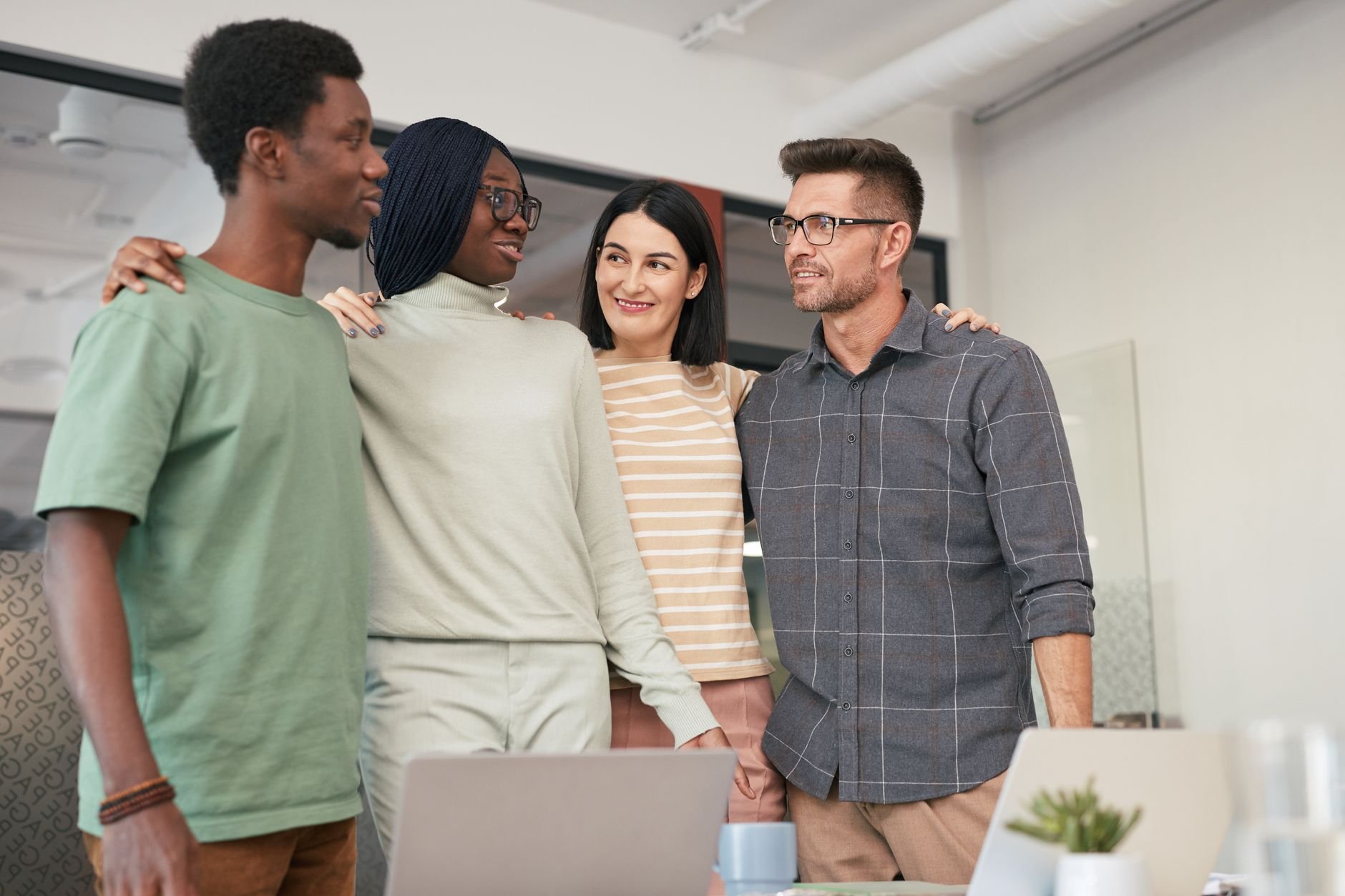 Four diverse colleagues sharing a moment of teamwork and collaboration in an office setting.